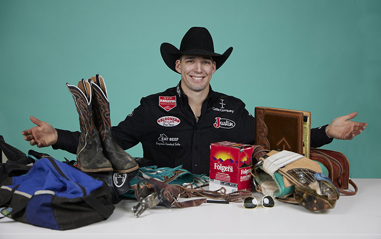 Jess Pope posing with arms open behind his boots, coffee, and other things on a desk.